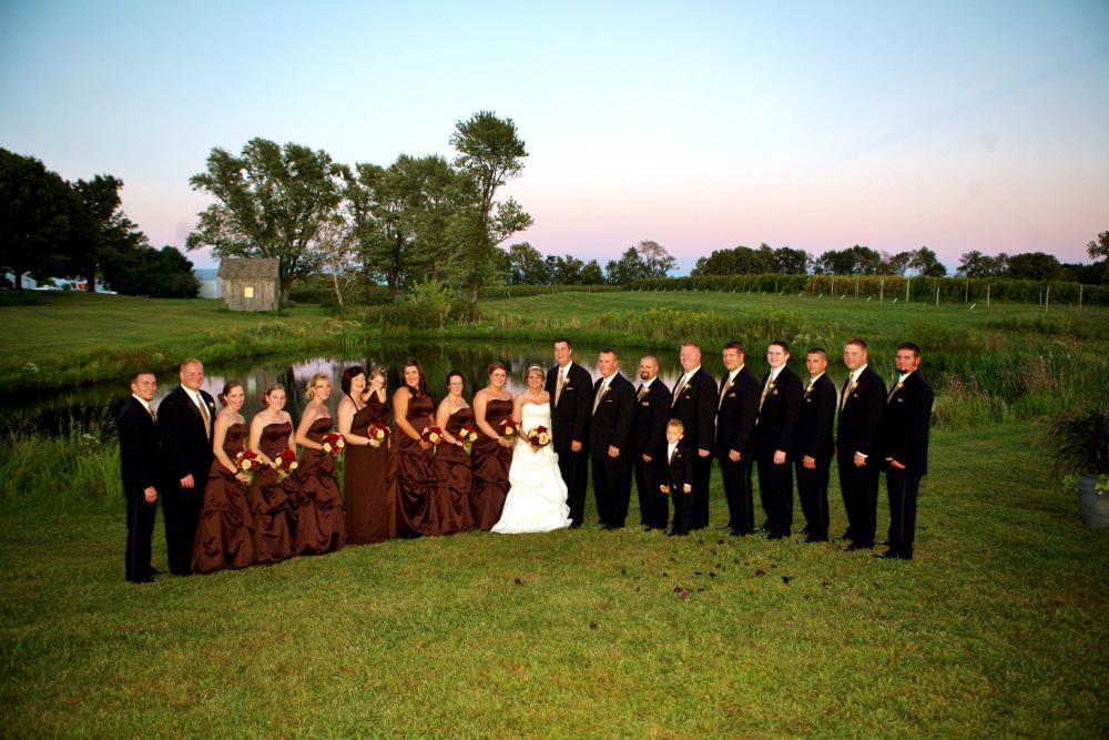 A group of people in suits and dresses standing on top of a grass covered field.