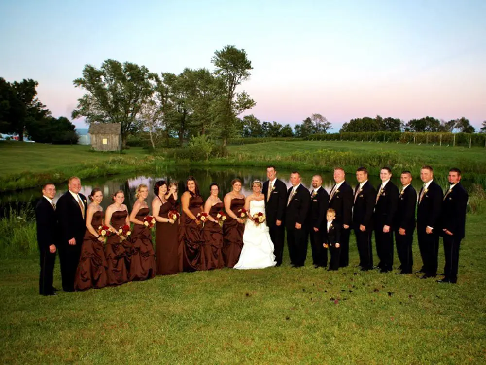 A group of people in suits and dresses standing on top of a grass covered field.
